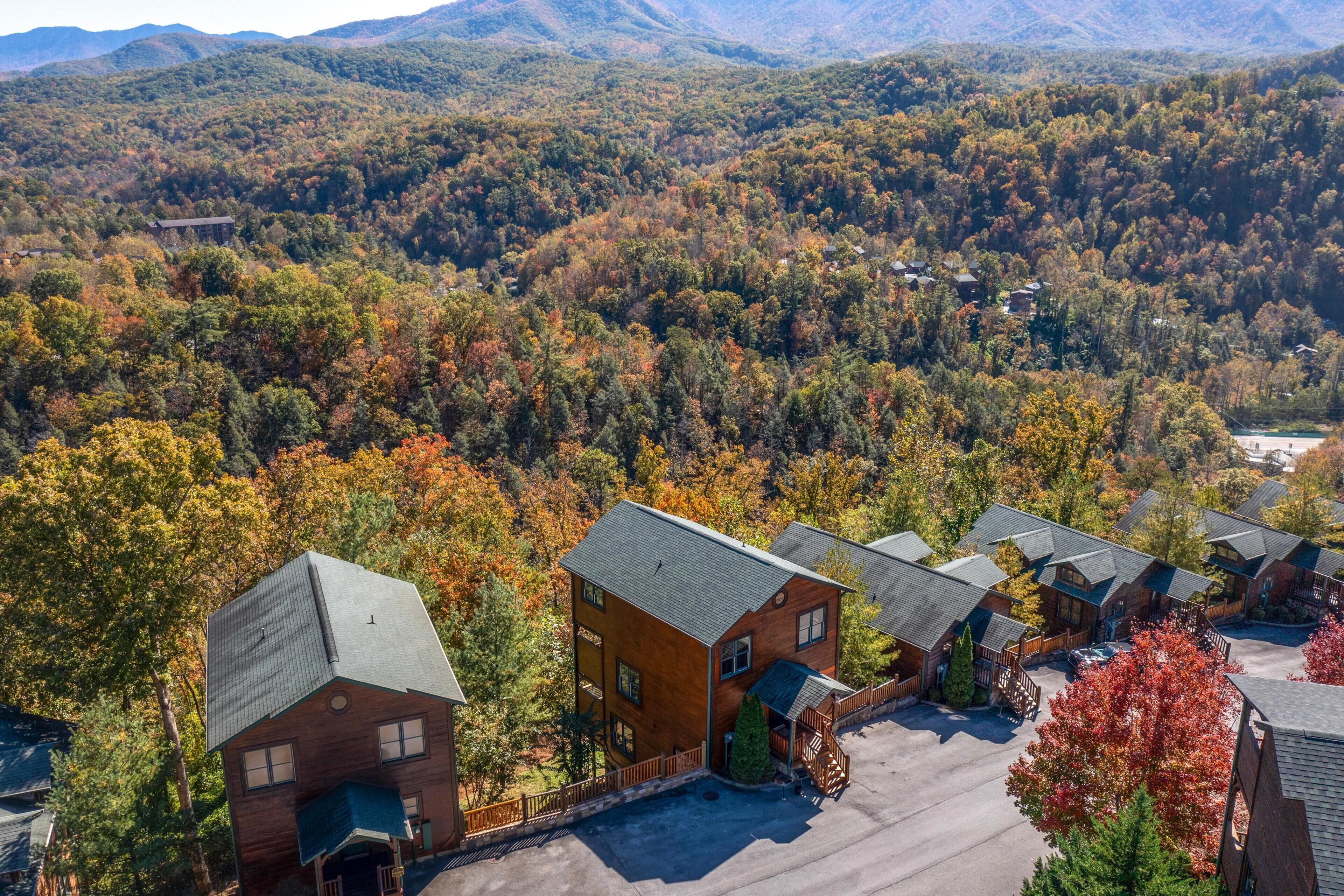 A lodge with multiple buildings, a parking area, and a forested backdrop.