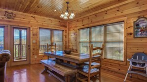 A wooden interior with a dining table, benches, and a high chair. - Morning Glory (Gatlinburg)