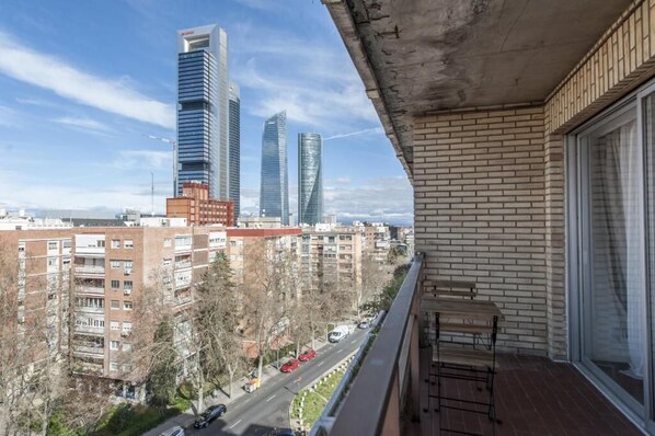 Un balcone con vista su alti edifici, un muro in mattoni e un tavolo.
