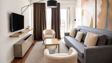 Una sala de estar moderna con una televisión de pantalla plana, un sofá, una mesa de centro y una silla.