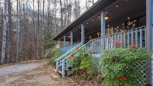 A wooden house with a porch, surrounded by trees and a gravel path. - Coyote Crossing (Sevierville)