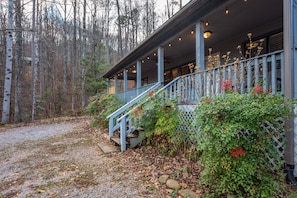 A wooden house with a porch, surrounded by trees and a gravel path. - Coyote Crossing (Sevierville)