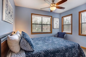 A bedroom with a bed, a ceiling fan, and three windows with blinds. - Coyote Crossing (Sevierville)