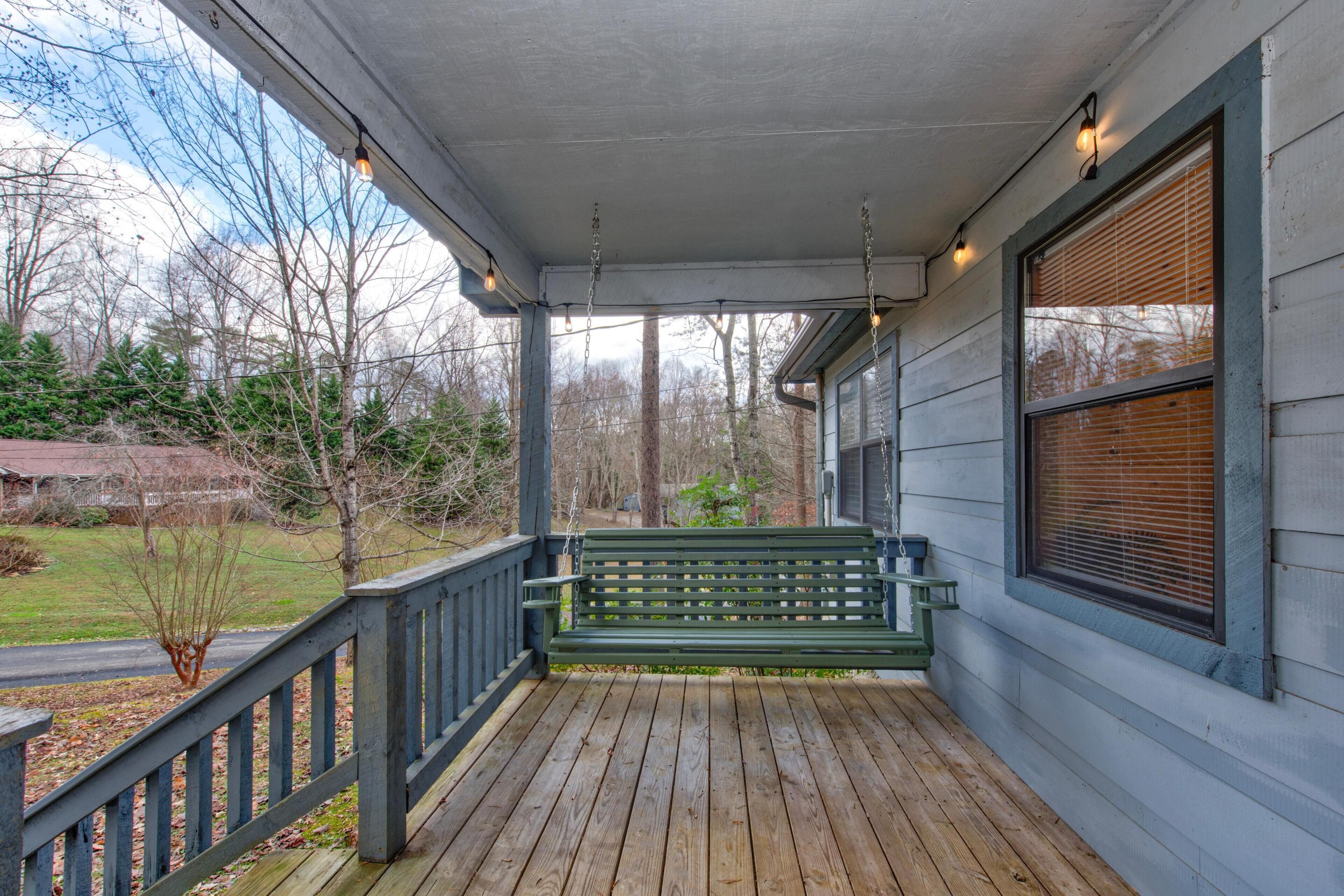 A wooden porch with a bench, a railing, and a window with blinds.