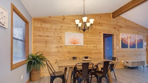 A wooden interior with a dining table, chairs, a chandelier, and artwork on the walls. - Coyote Crossing (Sevierville)