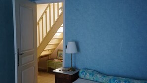 Una camera da letto con un letto, un comodino, una lampada, un comò e una scala che conduce a un piano superiore.