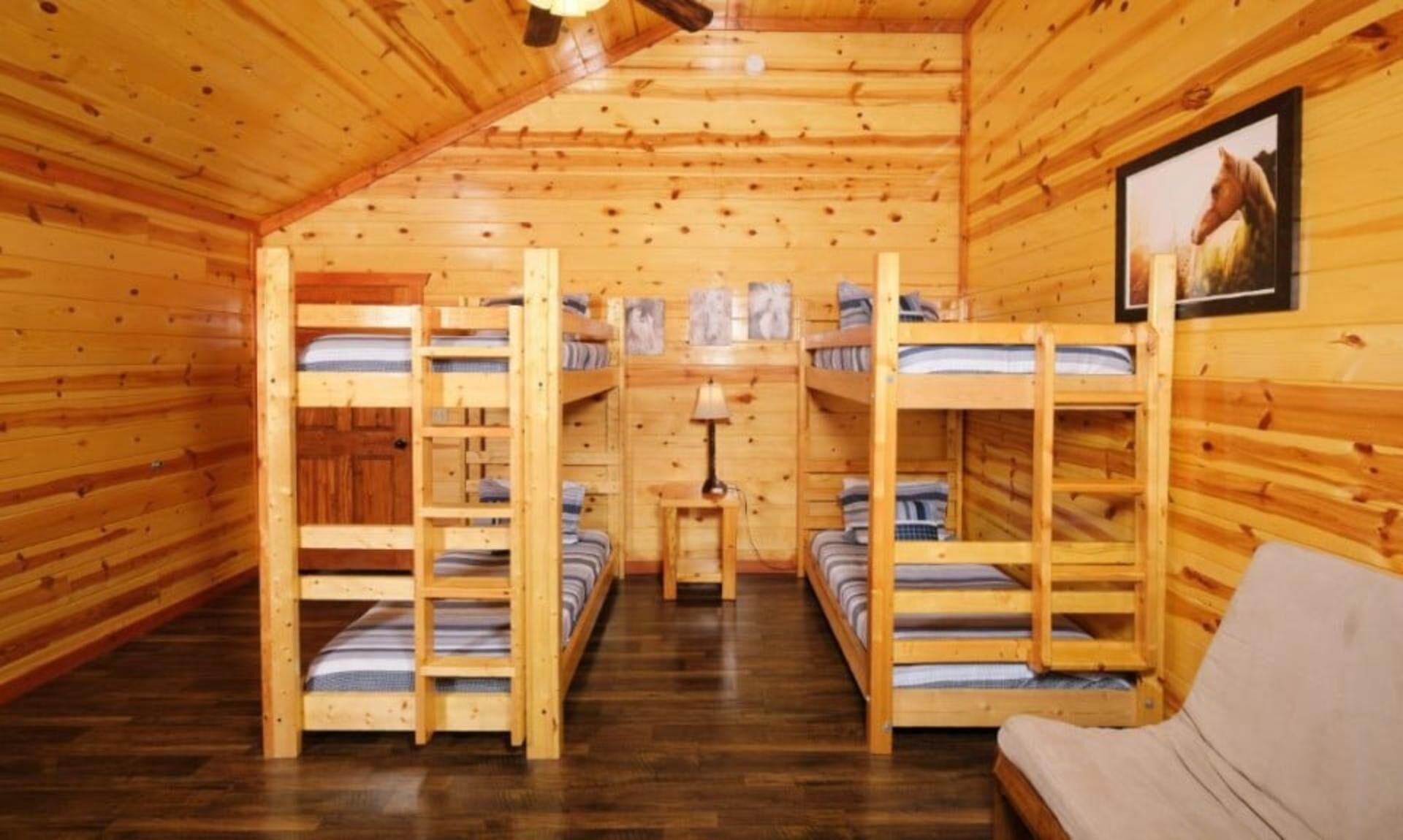 Une cabane en bois avec des lits superposés, une petite table et une lampe.