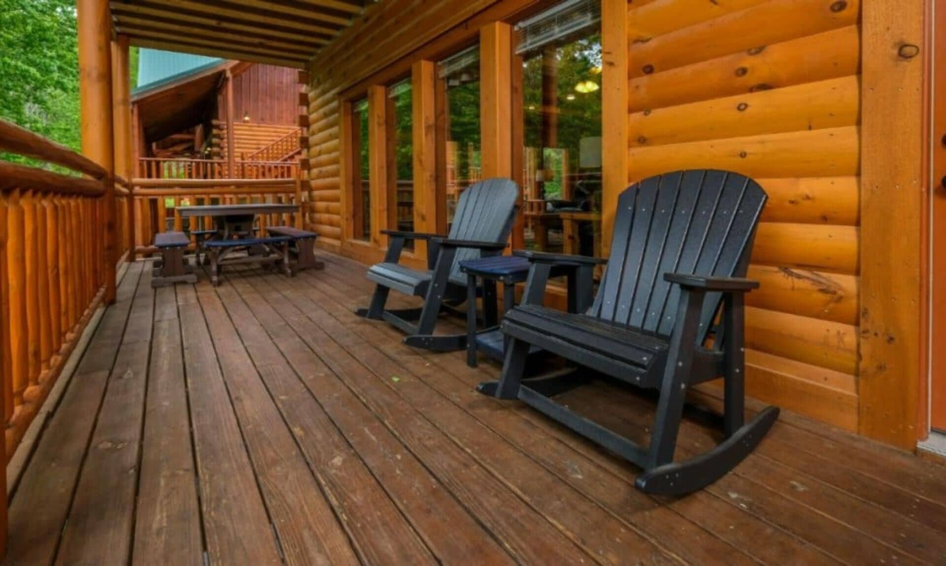 Puinen terassi, jossa on Adirondack-tyyliset tuolit, katettu oleskelualue ja näkymä sisätiloihin.