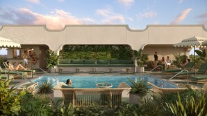 A pool area with lounge chairs, a seating area, and a wall with greenery. - The Warbler (New Orleans)