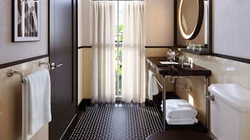 Un baño moderno con suelo de baldosas blanco y negro, un espejo grande, un inodoro y un lavamanos.