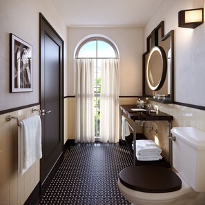 A modern bathroom with a black and white tiled floor, a large mirror, a toilet, and a sink. - The Warbler (New Orleans)