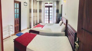 Ein Zimmer mit zwei Betten, einem fenster mit Vorhängen, einer Tür und einem Deckenventilator.