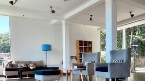 Ein großzügiger Wohnbereich mit Sofa, Sesseln, Couchtisch und Bücherregal.