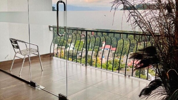 Ein Balkon mit freiem Blick auf die umliegende Landschaft, ein Stuhl und ein Blumentopf.