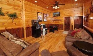 A wooden interior with a ceiling fan, two sofas, a small table, and a refrigerator. - Splash N Around (Sevierville)