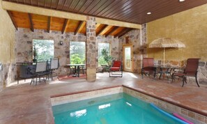 A pool area with stone walls, wooden beams, and outdoor seating. - Splash N Around (Sevierville)