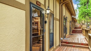 A building with a wooden deck, a glass door with a number sign, and a lamp post. - Innsbrook Vacation Condo 246 (Ruidoso)