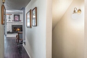 A hallway with a fireplace, framed pictures, and a wall-mounted light fixture. - Innsbrook Vacation Condo 246 (Ruidoso)