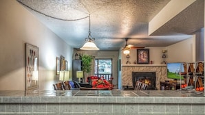 A living room with a fireplace, a television, and a stone fireplace surround. - Innsbrook Vacation Condo 246 (Ruidoso)