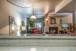 A living room with a fireplace, a television, and a stone fireplace surround. - Innsbrook Vacation Condo 246 (Ruidoso)