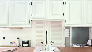 A kitchen with white cabinets, a wooden countertop, a gas stove, and two bar stools. - Mountain Creek Condo Waterpark Ski Resort (Vernon Township)