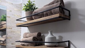 A bathroom with a mirror, towel rack, and wooden shelves holding towels and a vase. - Mountain Creek Condo Waterpark Ski Resort (Vernon Township)