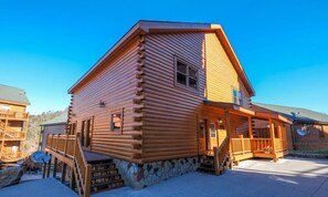 Eine Blockhütte mit Veranda, Treppe und gemauertem Fundament.