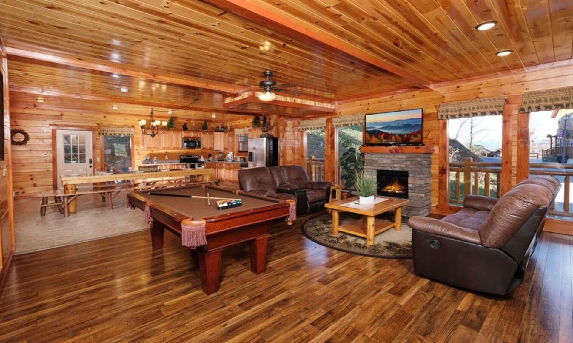 Een houten interieur met een pooltafel, een leren bank en een open haard.