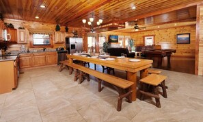 Ein Interieur einer Holzhütte mit Küche, Essbereich und Billardtisch.