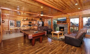 Ein Holzinterieur mit Billardtisch, Ledersofa und Kamin.