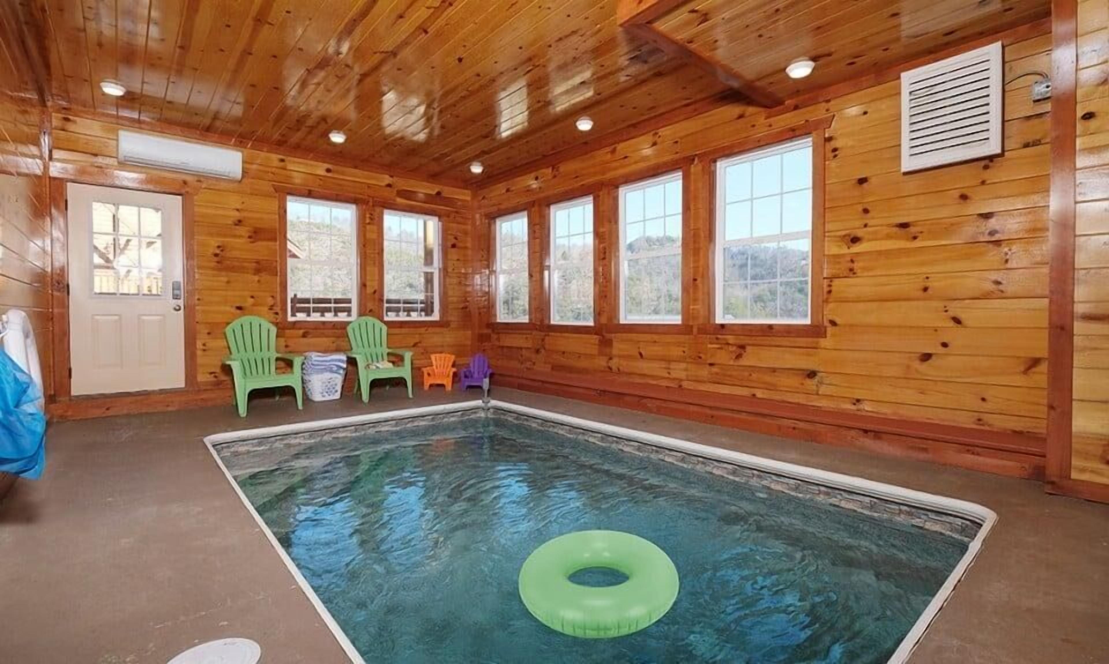 A wooden cabin with a pool, green chairs, and a door.