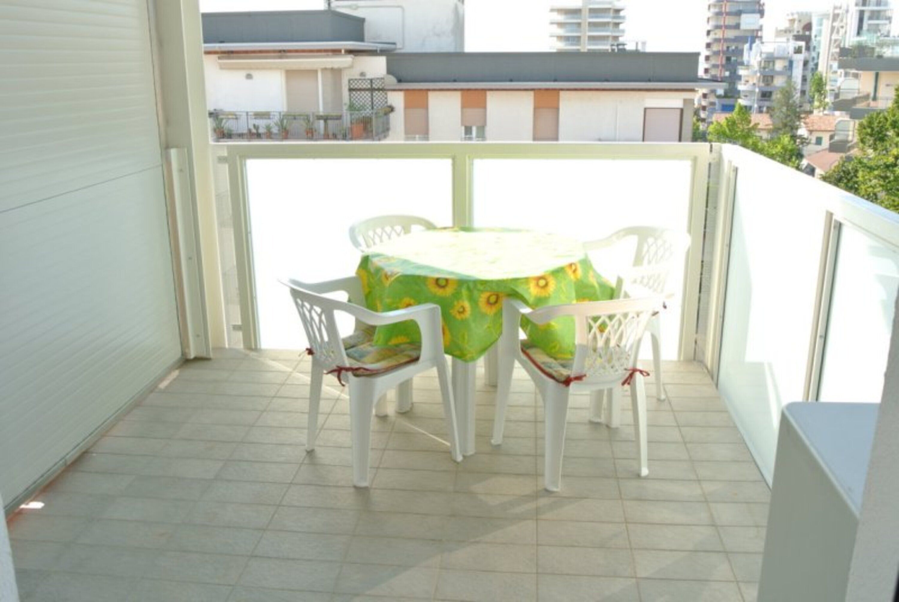 Ein Balkon mit Tisch und Stühlen, gefliestem Boden und Blick auf Gebäude.
