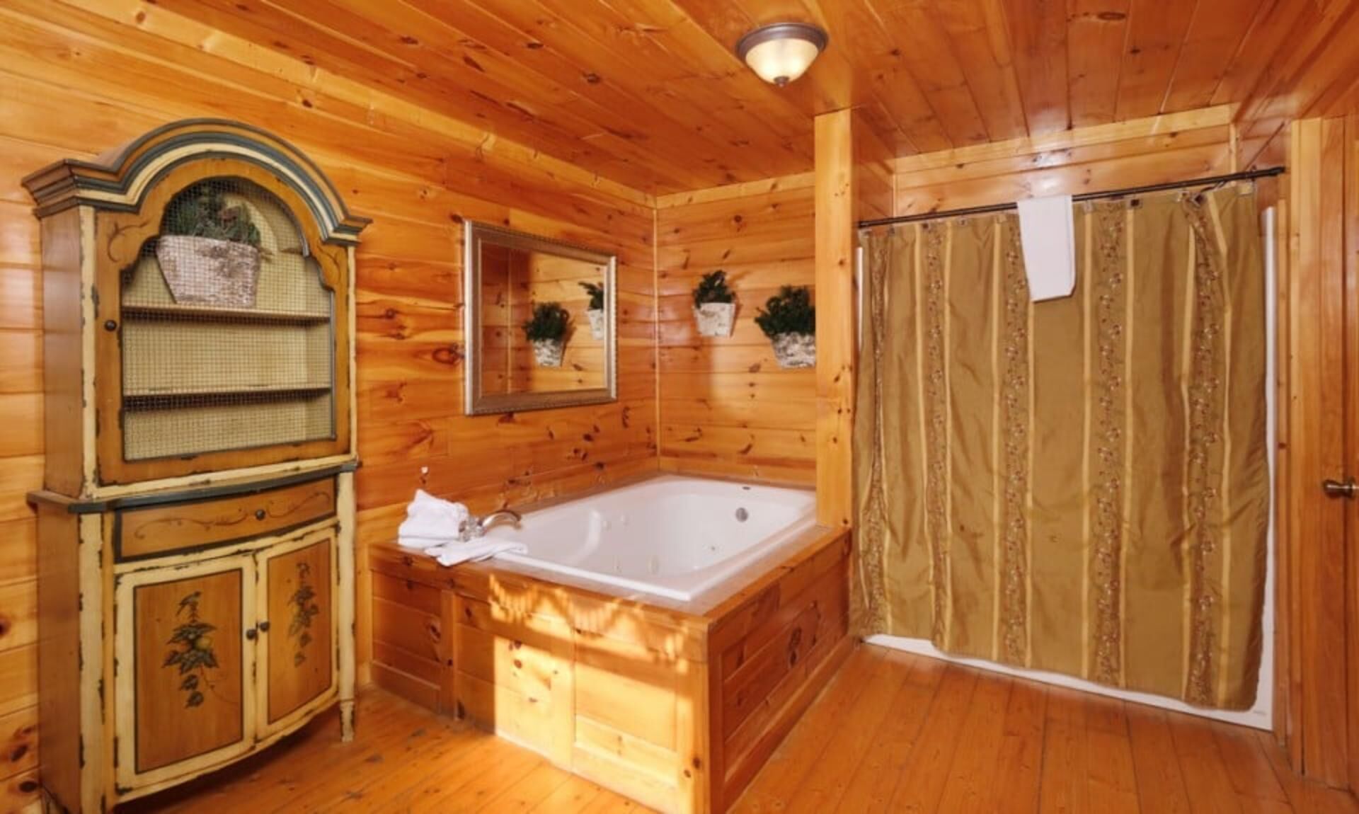 A wooden cabin interior with a bathtub, a vanity with a mirror, and a shower area.