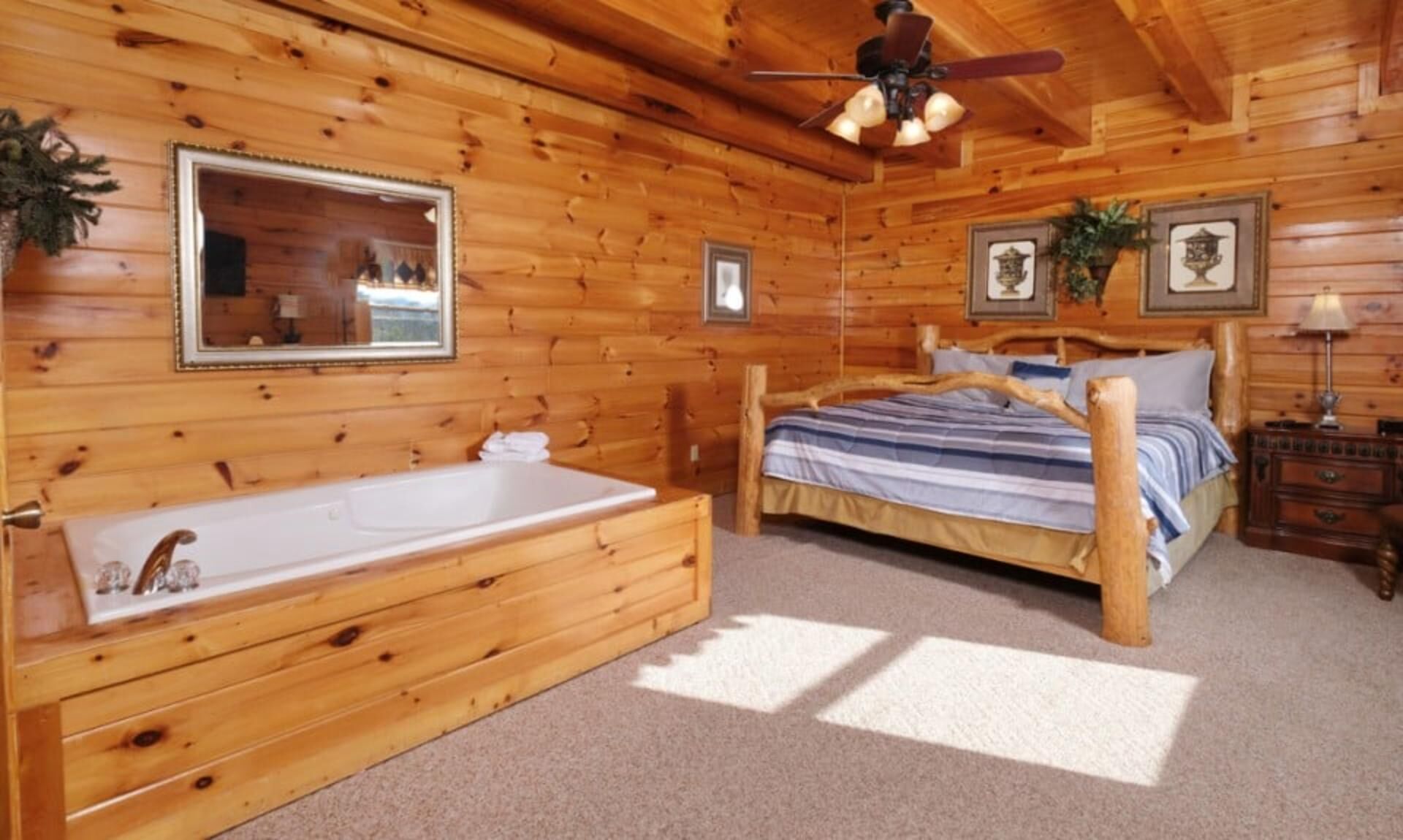 Un dormitorio tipo cabaña de madera con una cama de madera, un espejo grande, un ventilador de techo y una bañera.