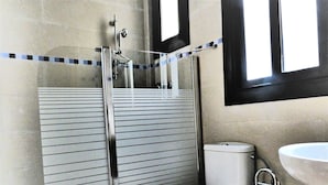 Un baño con ducha acristalada, inodoro y lavamanos.