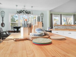 Una mesa de comedor de madera con un mantel tejido, un tapete tejido y una tabla de cortar de madera.