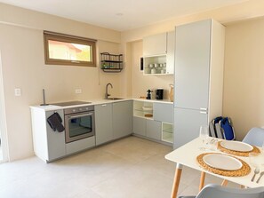 A compact kitchen with a built-in oven, a sink, and a dining area with a table set for two. - Lovely 1-bedroom apartment in charming Noord (Noord)