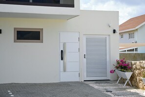 A modern building with a white exterior, a door, a window, and a wall-mounted light fixture. - Lovely 1-bedroom apartment in charming Noord (Noord)