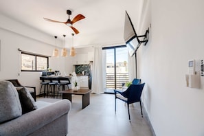 Ein modernes Wohnzimmer mit Sofa, Esstisch und Stühlen, einer Küchenzeile und einem Balkon mit Aussicht.
