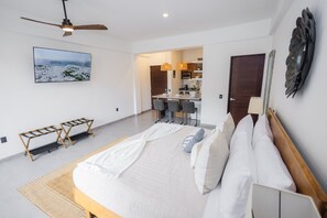 A modern hotel room with a bed, a ceiling fan, a dining area, and a view of the sea. - Vista Pedregal Comfortable Apartment in Cabo San Lucas Golden Zone (Cabo San Lucas)