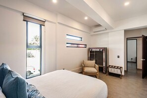 A bedroom with a bed, a chair, a wardrobe, and a window with a view of the outside. - Vista Pedregal New Apartment 5 min Walk to Marina (Cabo San Lucas)