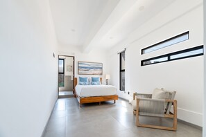 Ein modernes Schlafzimmer mit einem Bett, einem Sessel und einem Bild an der Wand.