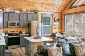 Una cocina moderna con una isla central, electrodomésticos de acero inoxidable y una zona de estar acogedora con un sofá de cuero.