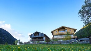 A wooden house with a balcony, surrounded by a field of yellow flowers and a mountain backdrop. - Vrbo Property (Prateria)