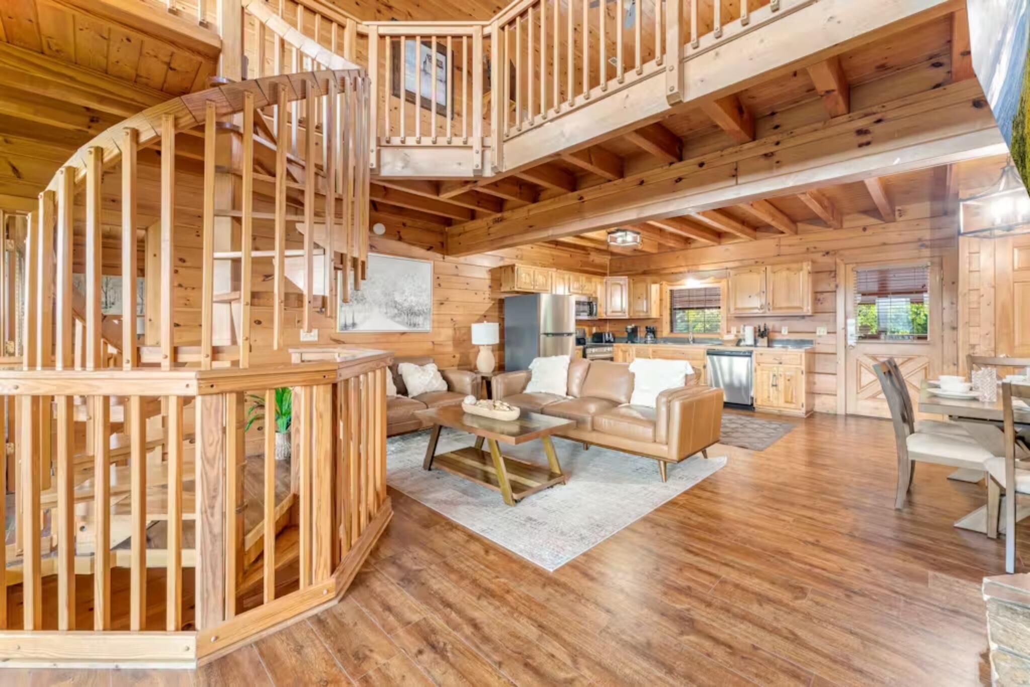 Interior d'una cabana de fusta amb zona d'estar, cuina i una escala de caragol.