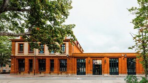 Un bâtiment à deux étages, doté d’une façade en briques, de grandes fenêtres et d’une entrée imposante avec une enseigne.