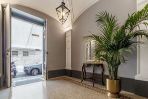 Ein Eingangsbereich mit geparktem Auto, einem Blumentopf, einem Spiegel auf einer Konsole und einem gemusterten Teppich.