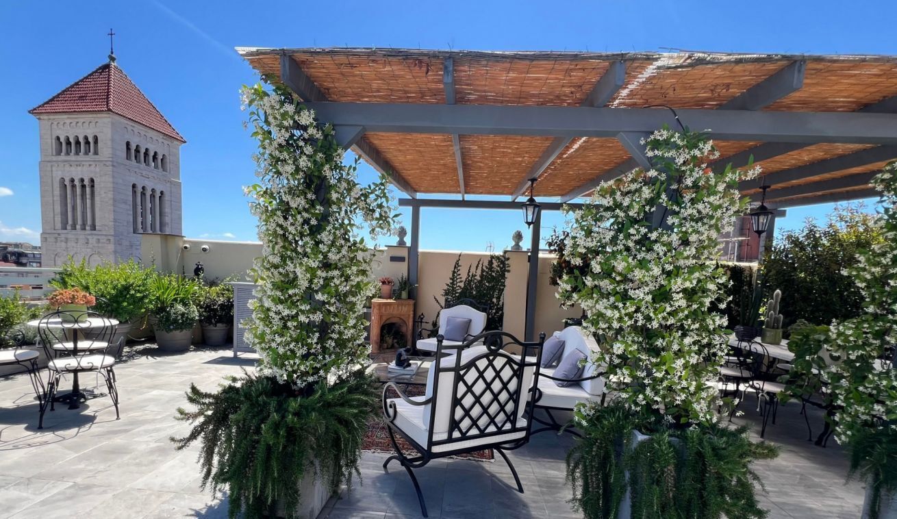 An outdoor patio with seating, a pergola, and a tower in the background.