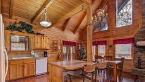A wooden cabin interior with a kitchen, dining area, and a fireplace. - Secluded Hideaway (Pigeon Forge)