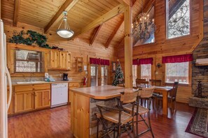 A wooden cabin interior with a kitchen, dining area, and a fireplace. - Secluded Hideaway (Pigeon Forge)